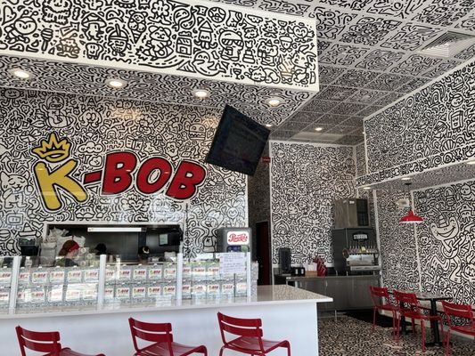 Two guests toasting with K-BOB boba drinks in front of the doodle wall