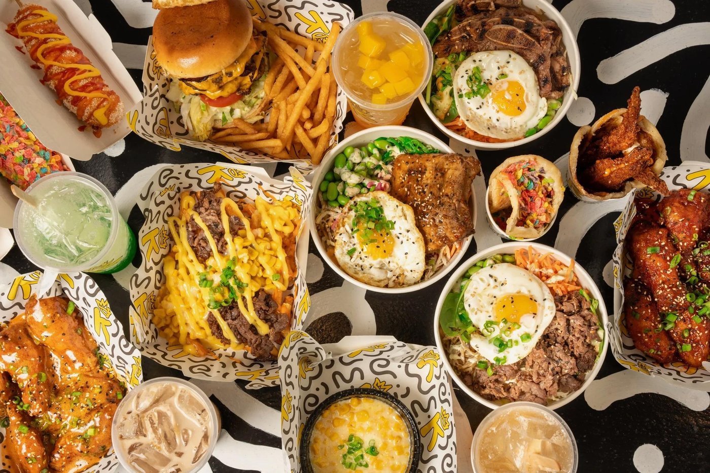 K-BOB signature spread — Krazy Wagyu burger, Takis corn dog, loaded bulgogi fries, and wings on the hand-painted doodle table