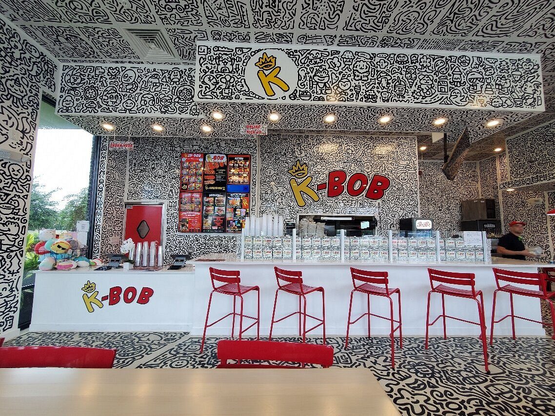 K-BOB dining room with red chairs, doodle-patterned tables, and the K-BOB service counter