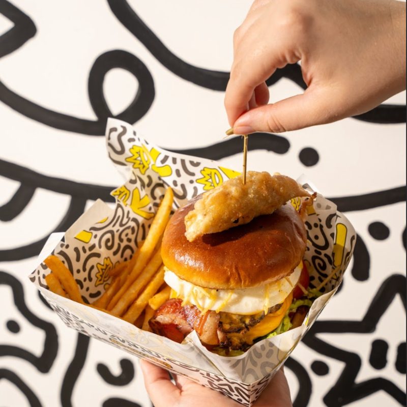 K-BOB Krazy Wagyu Burger with pork belly in a doodle-print box with fries